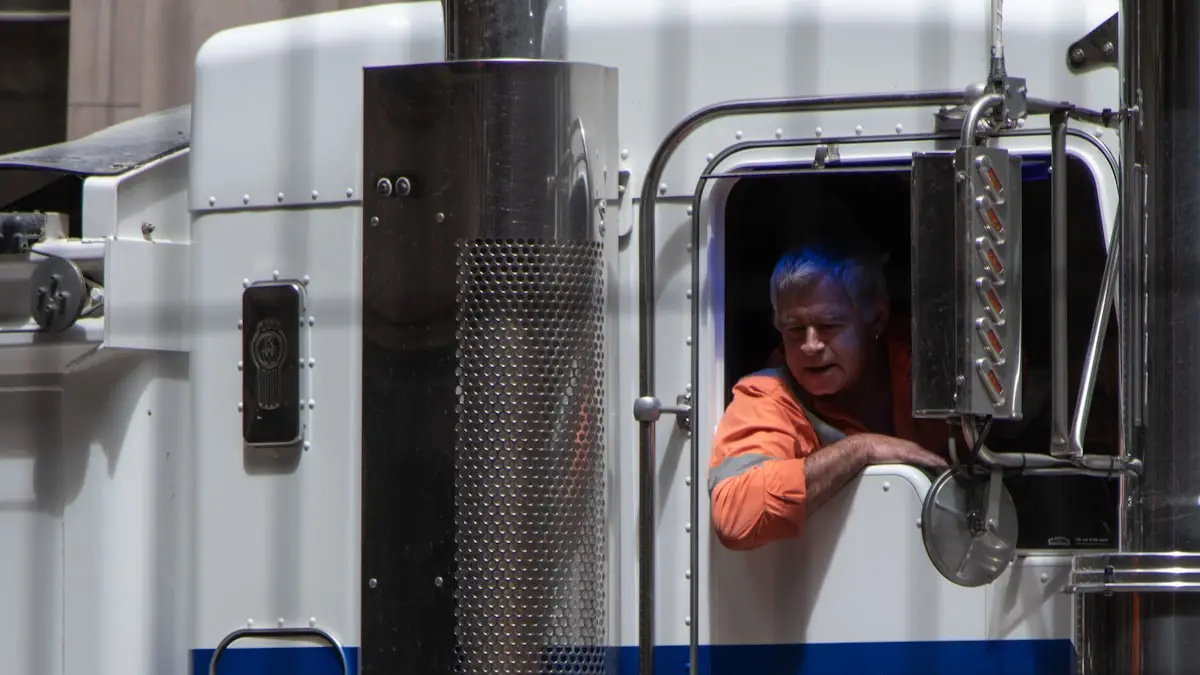 A driver standing in front of a parked freight truck