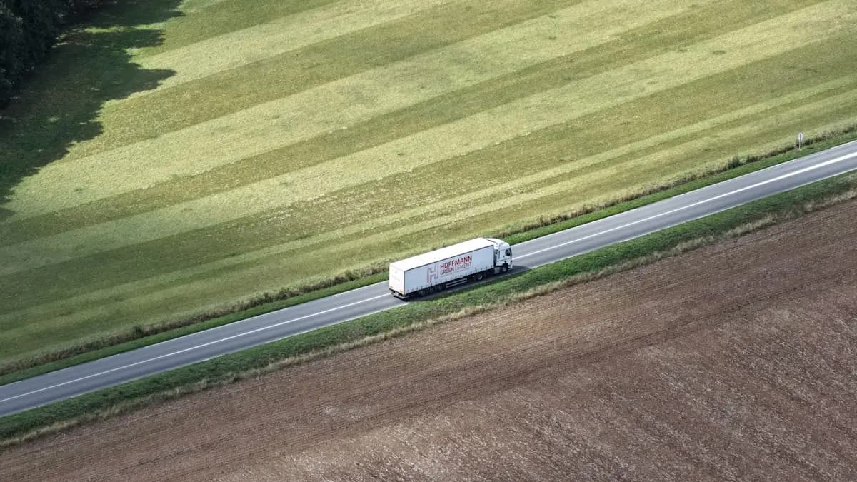 A white truck on a rural road running through open farmland